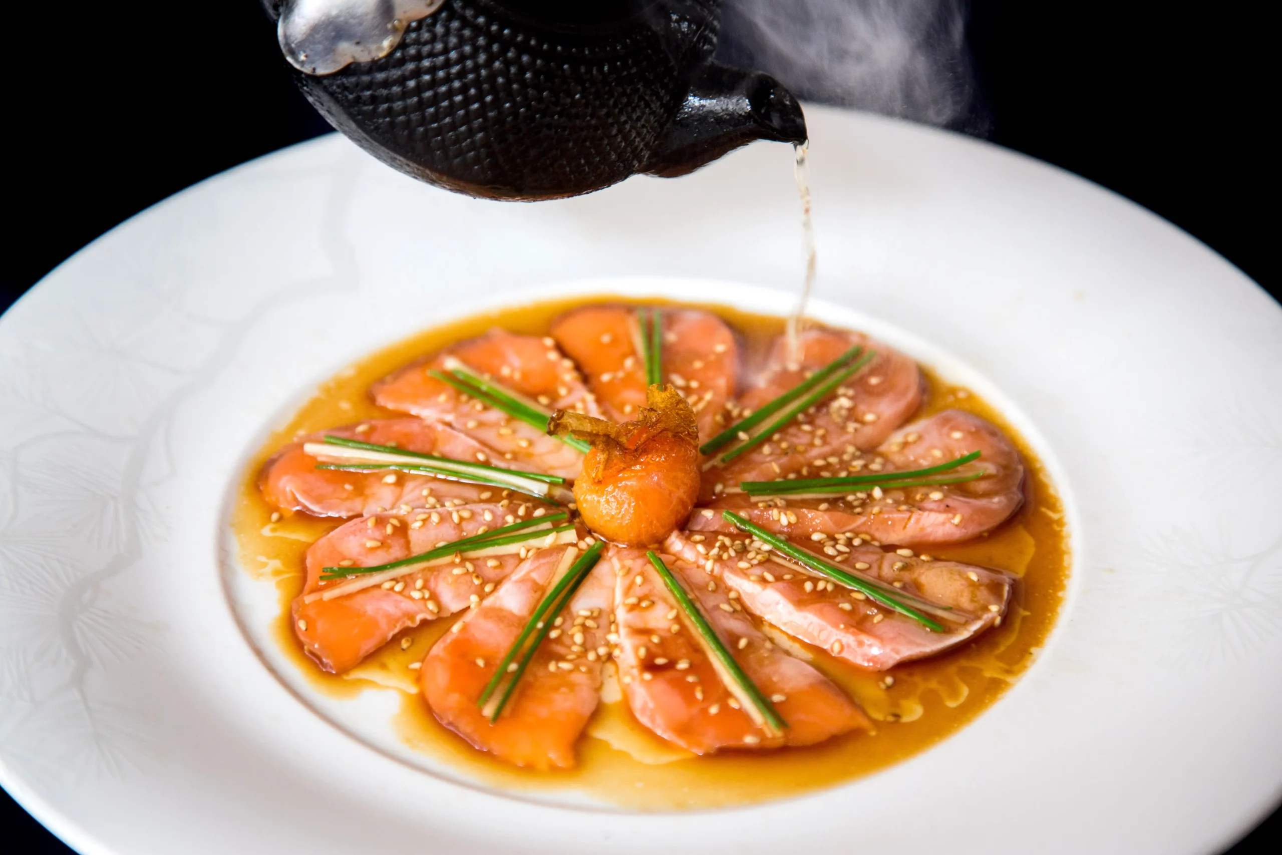 Nobu’s signature New Style salmon sashimi with chives and sesame, finished with hot oil from a teapot